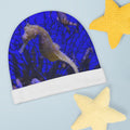 Baby hat with seahorse design on a blue background, surrounded by yellow starfish.