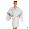 Front facing woman wearing the moontiq white kimono robe 'I Got Wings' with black angel feathers on the sleeves against a white background