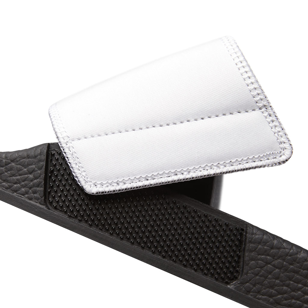 Close up of the removable and washable white strap of the moontiq 'I Got Wings' women's slide sandals with a black insole on a white background