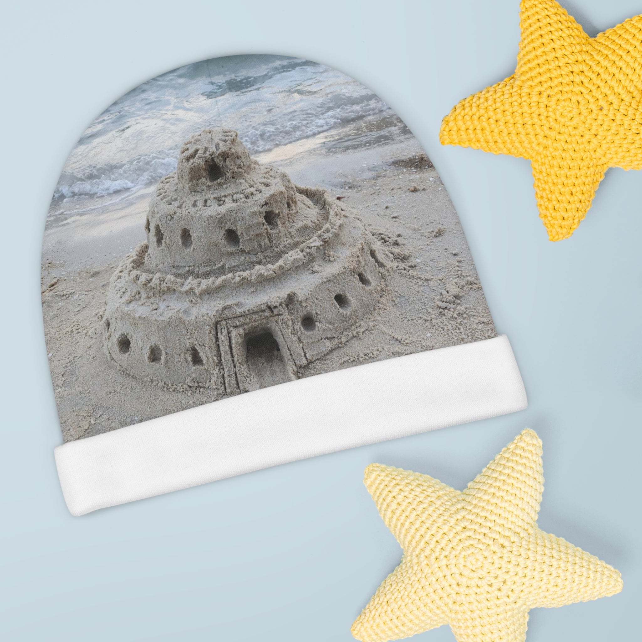 moontiq soft baby beanie for newborns up to six months featuring a sandcastle on the beach.